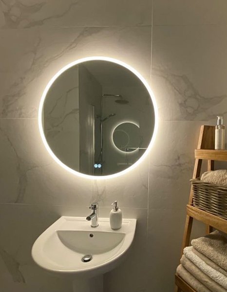 round bathroom mirror above white sink