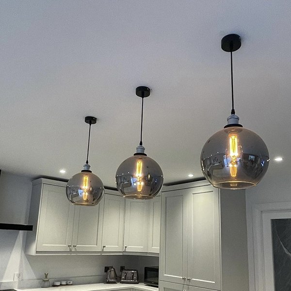 three smoked glass dome pendant lights with chrome features above a kitchen island