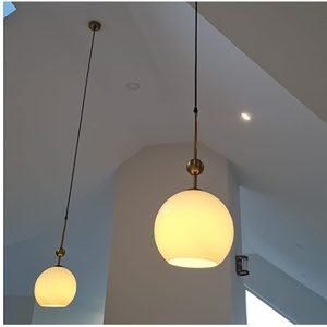two white glass sphere pendant lights hanging above a kitchen island