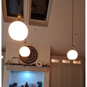 Three White Sphere Lights with Golden Handles Hanging in a kitchen