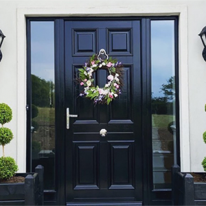 two black wall lanterns fixed to a front porch beside a black front door