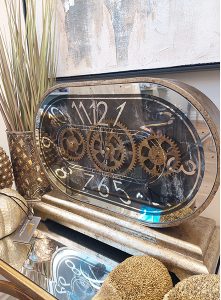 golden clock showing internal mechanisms beside a pot plant
