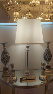 Table lamp with box shade and chrome stem illuminated on a console table